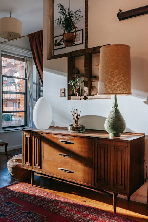 Free Vintage wooden cabinet on parquet floor with carpet decorated with stylish lamps and plants in spacious room in daylight Stock Photo