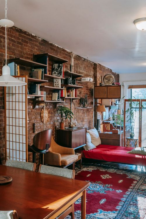 Free Interior of stylish loft room with classic wooden furniture near brick wall and ornamental rug in sunlight Stock Photo