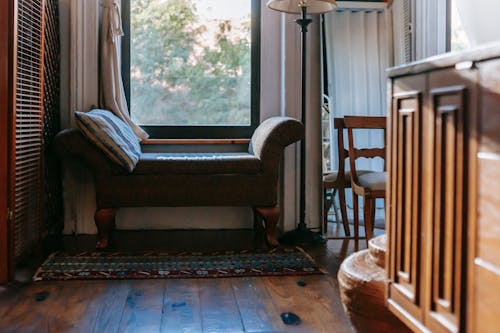 Elegant ottoman bench placed under window in elegant room