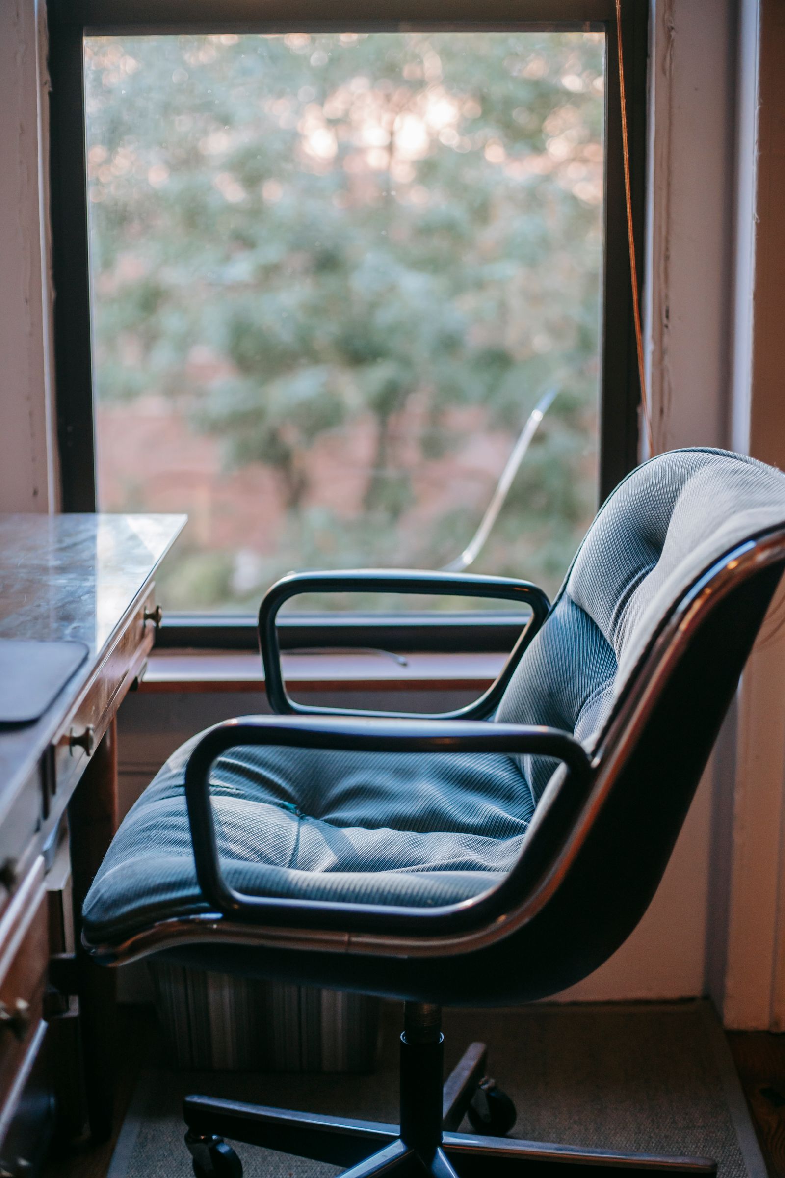 Elegant office chair and wooden desk beside a window