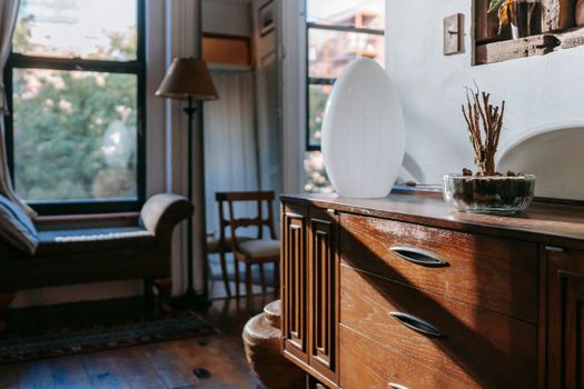 Interior of contemporary home with vintage wooden commode with drawers in shadow of daylight