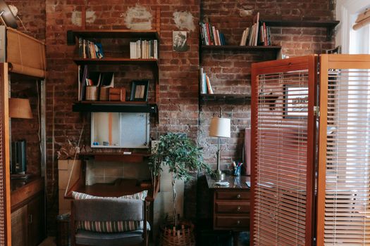 Modern room in loft style with wooden screen and different books placed on shelves