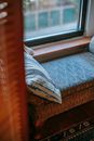 Soft pouffe with cushion near window and rug