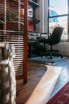Cozy light room with aged wooden table with drawers and office chair in sunny day
