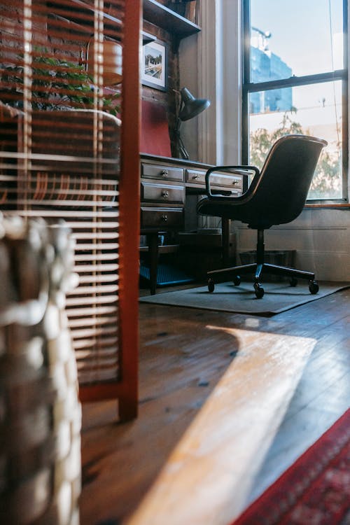 Free Cozy light room with aged wooden table with drawers and office chair in sunny day Stock Photo