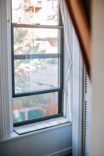 Closed double hung window placed in cozy light room in apartment in daytime