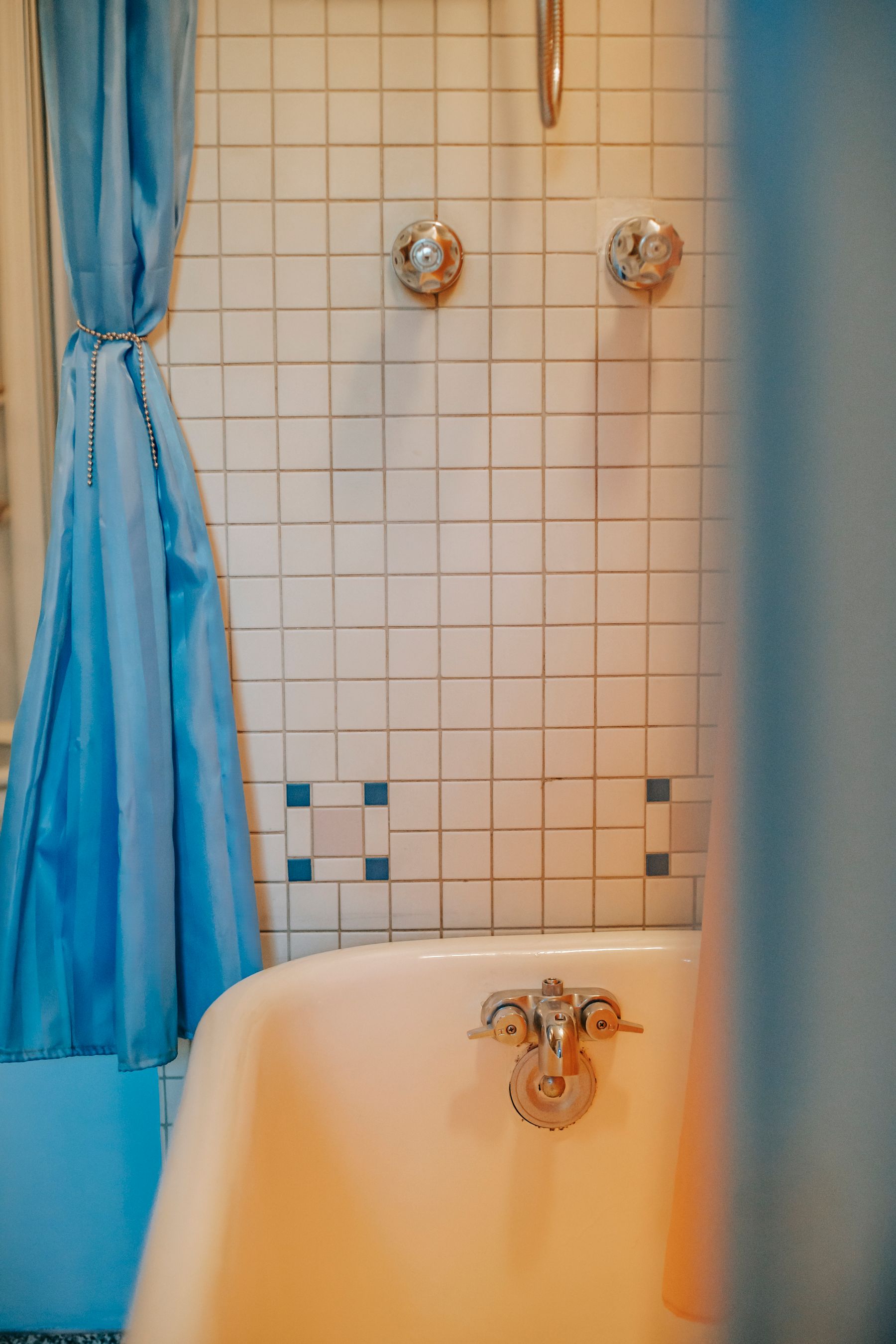 Vintage bathroom with blue tile, bathtub and shower curtain