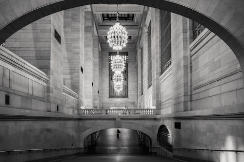 Black and white of old interior of passage under stone bridge with railing and brick columns