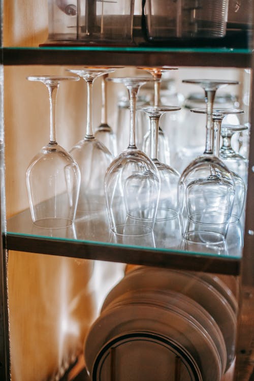 Glass and ceramic plates on wooden shelves under glass in kitchen at home