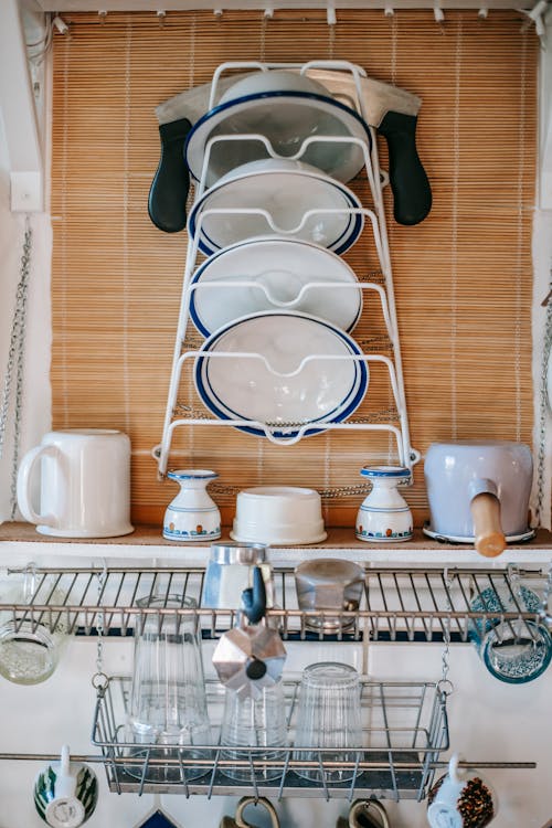 Interior of kitchen with ceramic dishes and glass on metal shelves at home