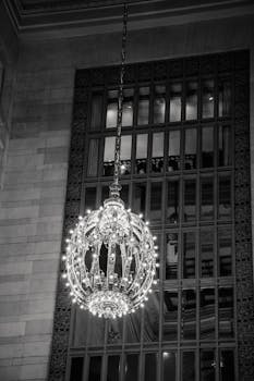 Black and white photo of a chandelier in Grand Central Terminal, NYC, showcasing elegant architecture.