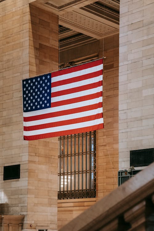 Американский флаг висит между колоннами в каменном здании