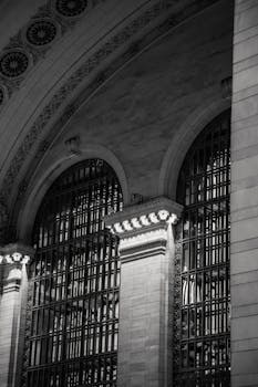 Black and white image of Grand Central Terminal arches and windows showcasing architectural elegance.