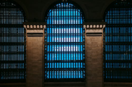 Facade of architectural construction with arched windows covered with lattice and brick pillars with projector light