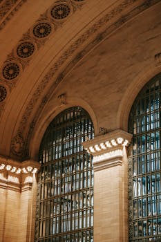 From below of ornamental ceiling of Grand Central Terminal over window with metal lattice in classic structure