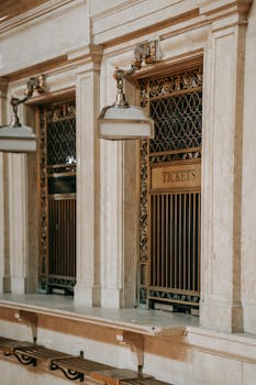 Interior of classic railway station of Grand Central Terminal with metal lattice on ticket window under old chandeliers
