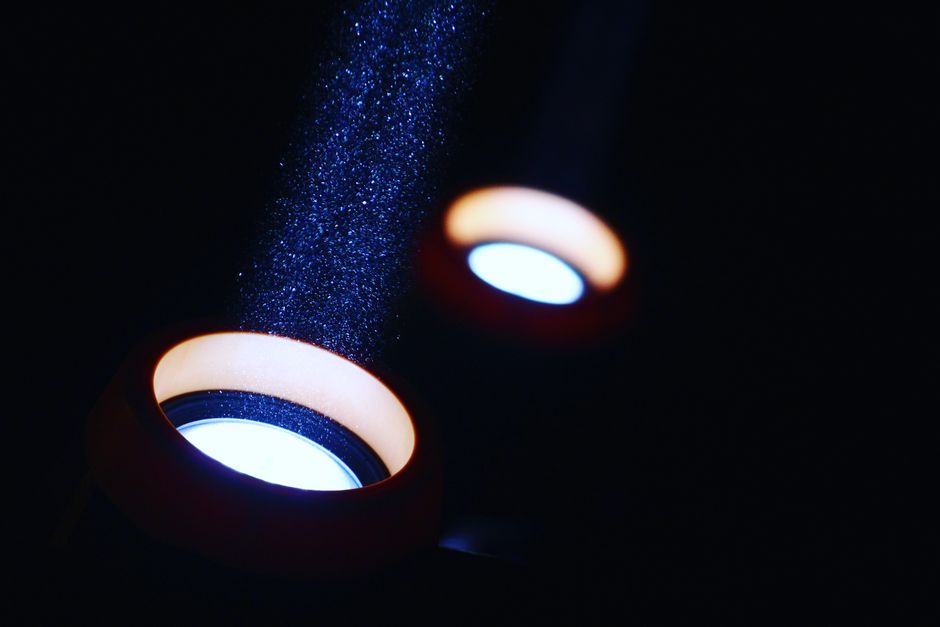 A striking visual of light beams illuminating particles in a dark setting, creating an abstract effect.