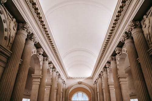 Free Interior of grand classic palace passage with majestic stone colonnade beneath arched white ceiling and ornamental stucco works Stock Photo