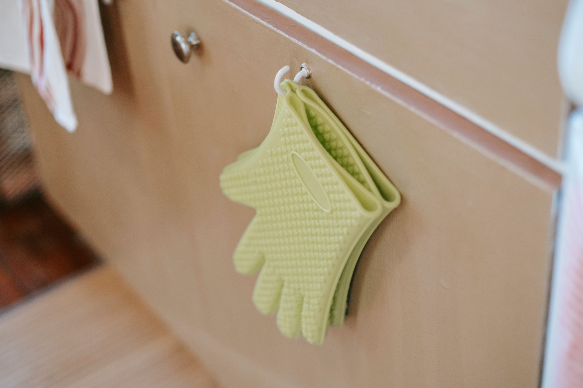 Pair of oven gloves on cabinet door in kitchen