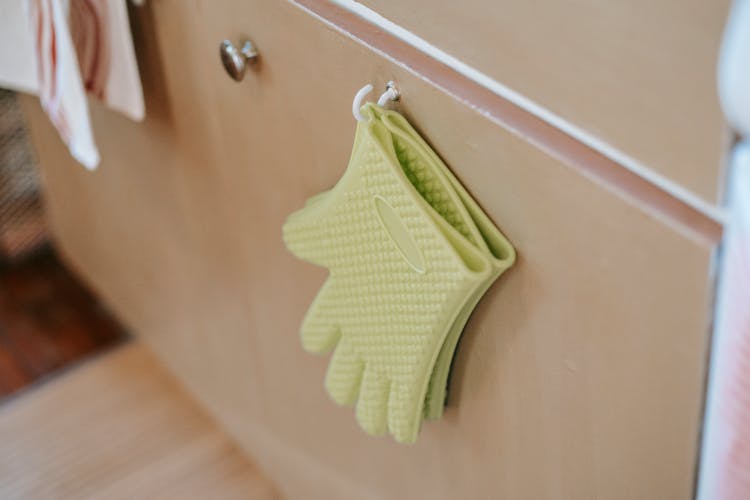 Pair Of Oven Gloves On Cabinet Door In Kitchen