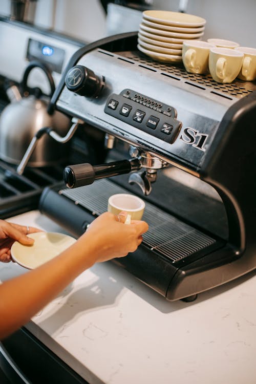 Person with ceramic cup preparing coffee in machine