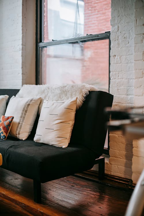 Free Interior of cozy room with comfortable sofa with pillows near window in loft style apartment Stock Photo