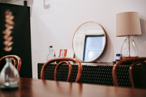 Interior of cozy living room with wooden table and chairs with mirror and lamp placed on shelf