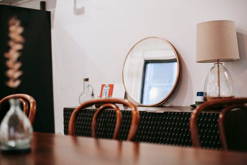 Free Interior of cozy living room with wooden table and chairs with mirror and lamp placed on shelf Stock Photo