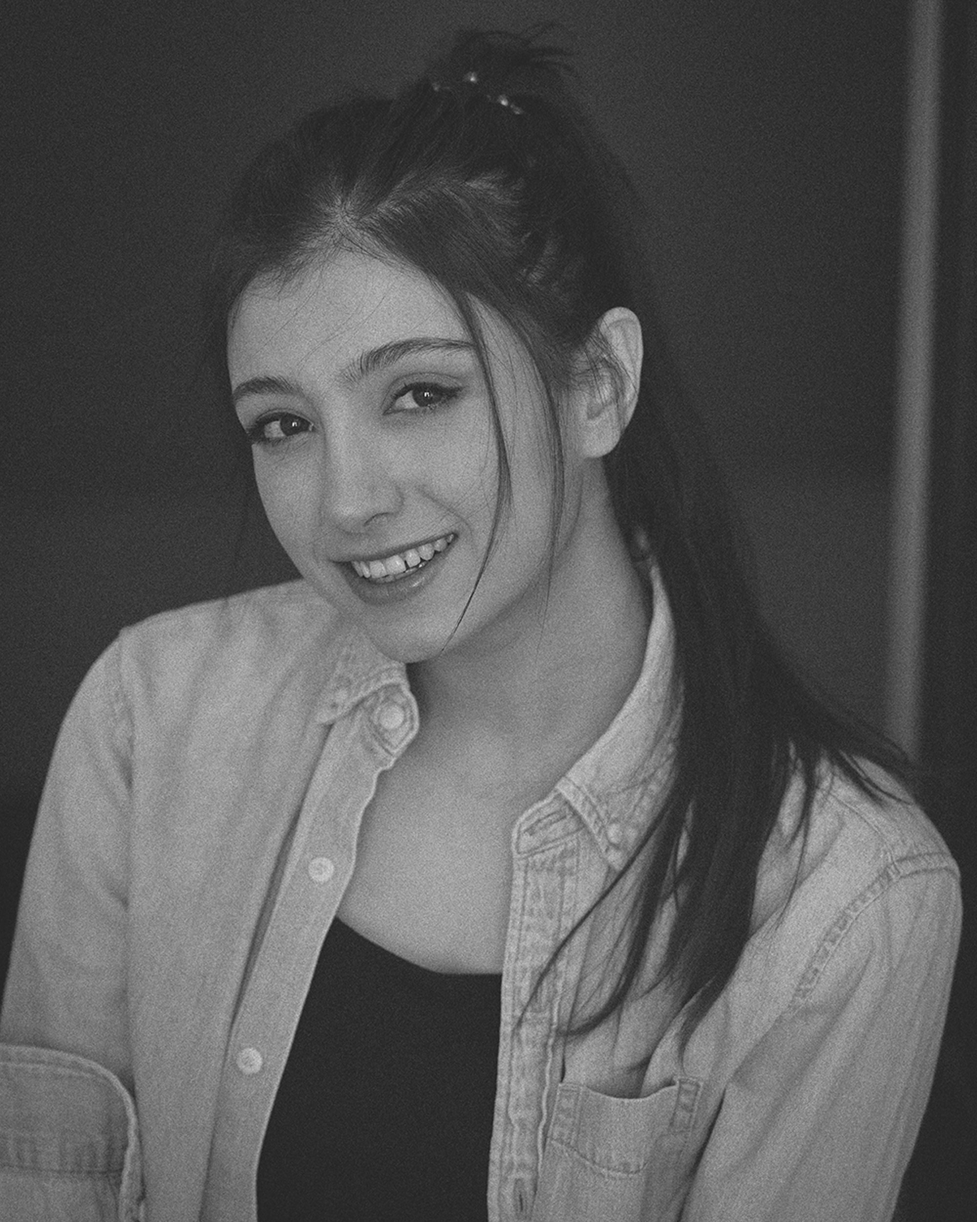 Charming black and white portrait of a smiling woman, showcasing elegance and style.