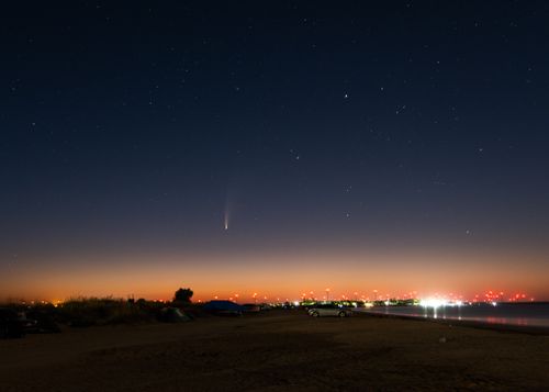 Free Calm night sky with stars and city lights by the beach, perfect for peaceful evening themes. Stock Photo