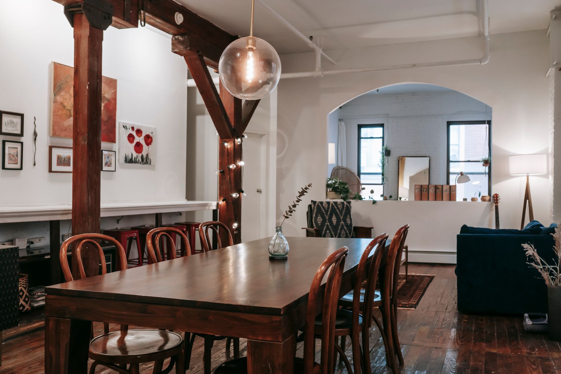 farmhouse apartment layout for cozy homes Interior of wooden table with glowing lamps hanging on pillar in creative light living room with furniture and arched aperture