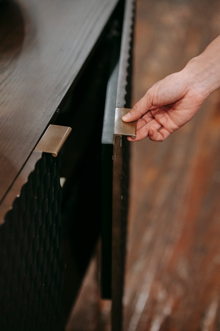 Crop Person Opening Door Of Wooden Cabinet At Home