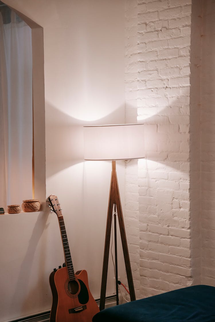 Classical Guitar Near Floor Lamp In House