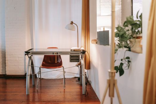 Room with lamp on rectangular shaped table on wooden floor near potted plant at home