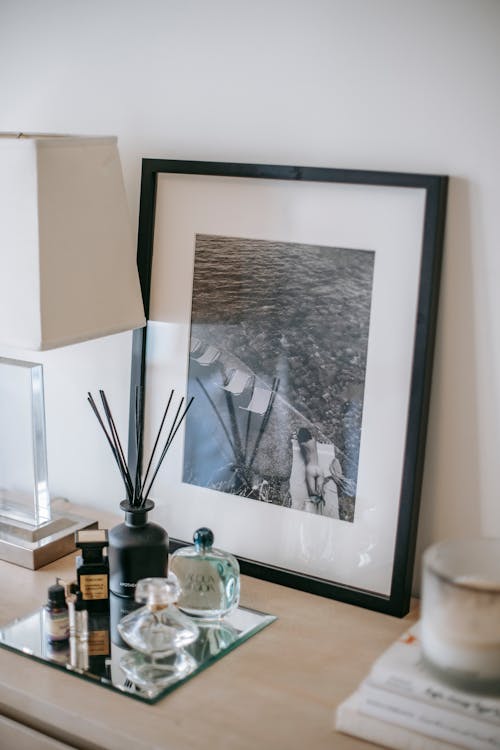 Photography in frame near perfume bottles and incense sticks with lamp near wall at home