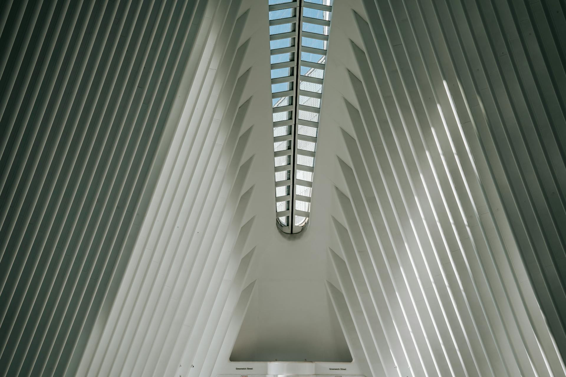 Low angle view of the modern architectural design inside the Oculus in NYC, featuring a glazed skylight.