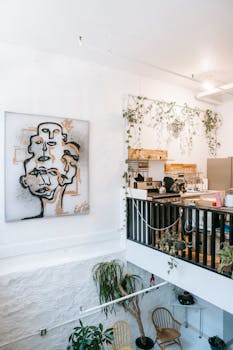 Bright loft space featuring plants, modern art, and a kitchen view.