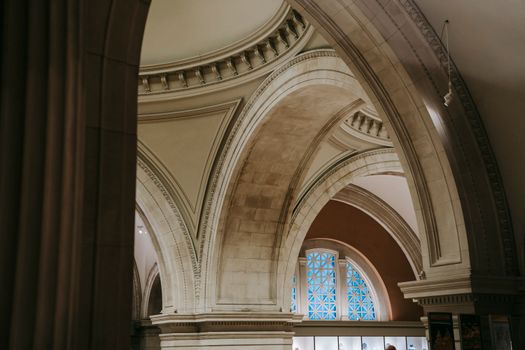 From below of museum hall with arched passages with ornamental decoration on ceiling and illuminated with lamps