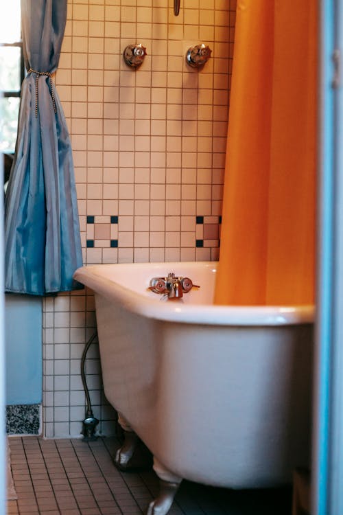Interior of bathroom with orange curtains and tiled floor and walls