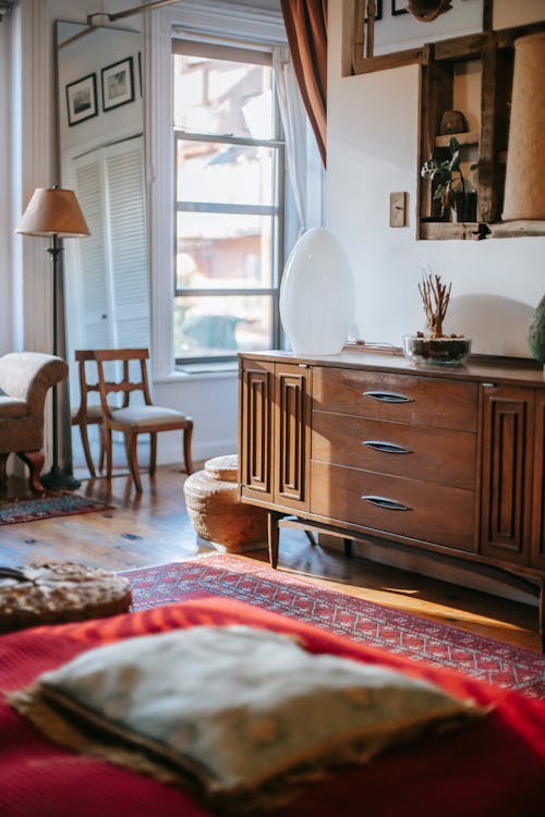 Old fashioned dresser near white wall in cozy bedroom