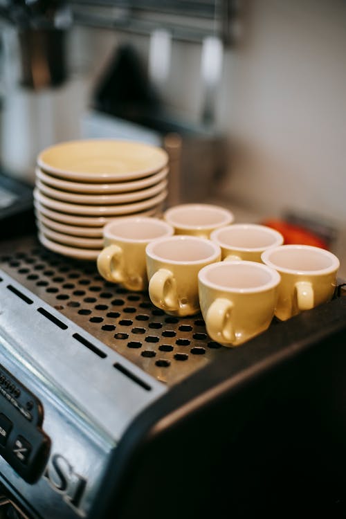 Set of colorful coffee cups and saucers standing on coffee machine in kitchen