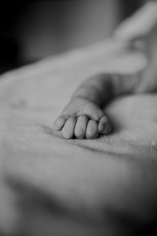 Free Crop calm newborn baby resting on bed Stock Photo