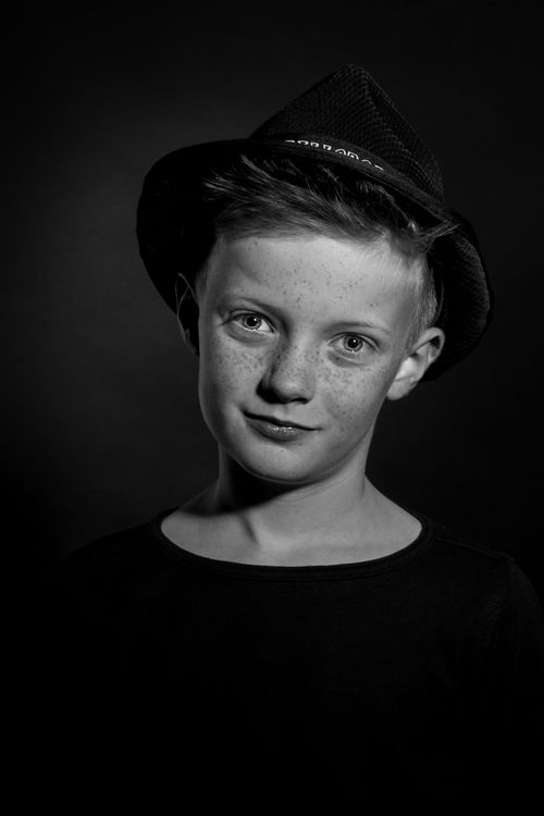 Free Monochrome portrait of a young boy wearing a fedora, looking confidently at the camera. Stock Photo