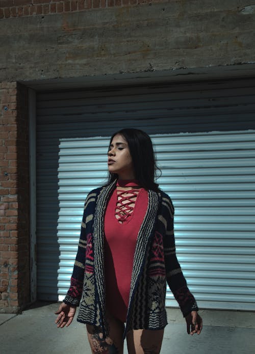 Stylish ethnic lady standing near building