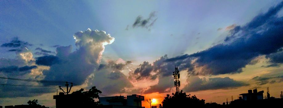 Dramatic sunset in Wadgaon, India, showcasing vibrant clouds and a silhouetted skyline.