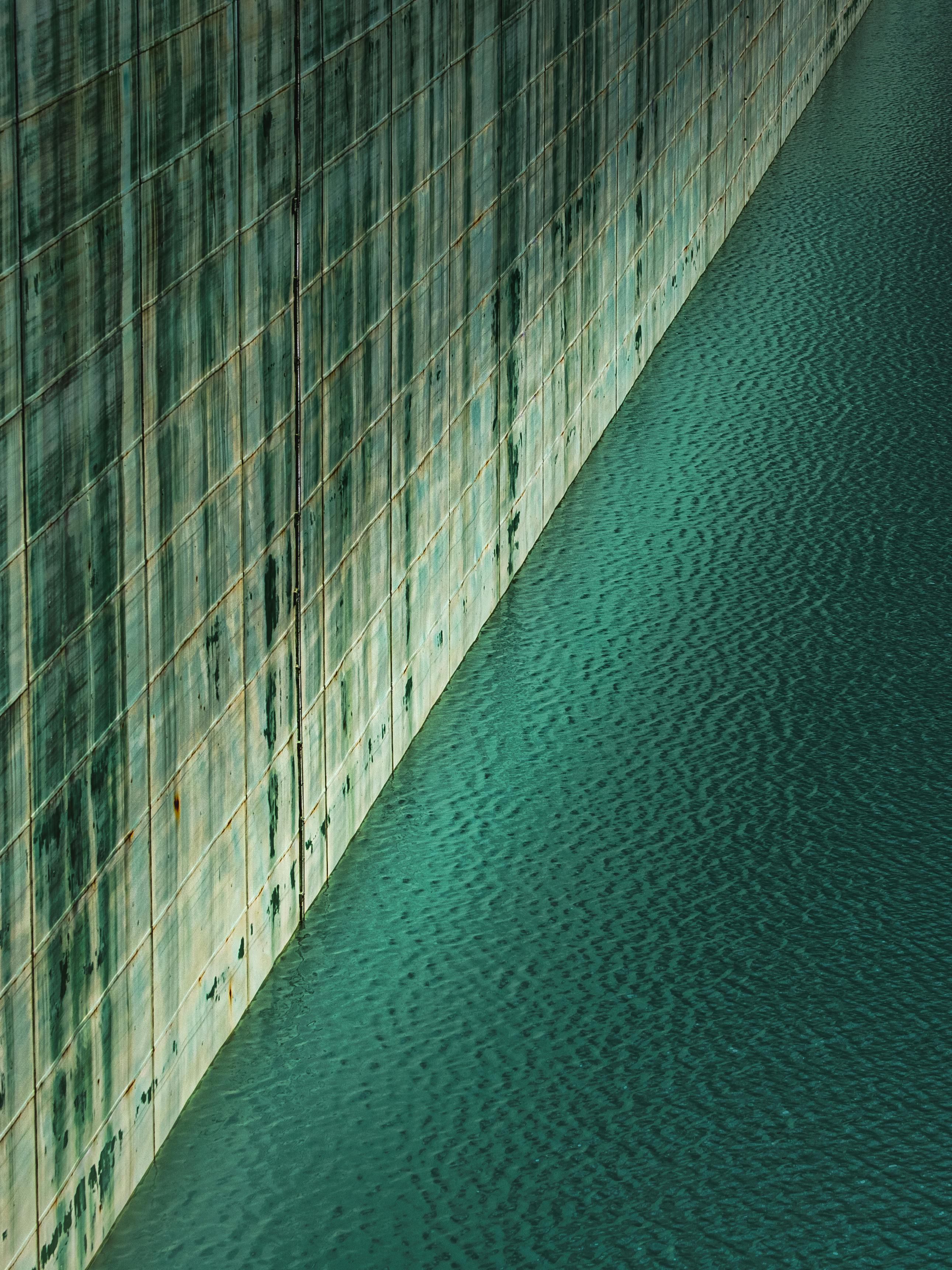 Vertical shot of a textured wall reflected in calm water in Lombardy, Italy.