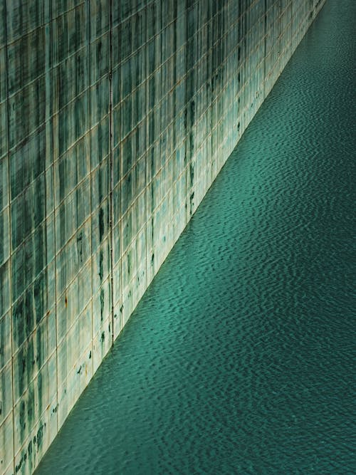 Body of Water Beside the Green and White Concrete Wall