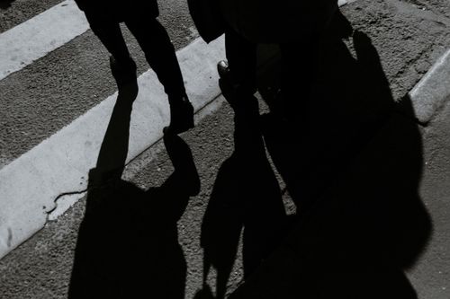 Free From above black and white of crop anonymous people walking on roadway with crosswalk and shadows in city Stock Photo