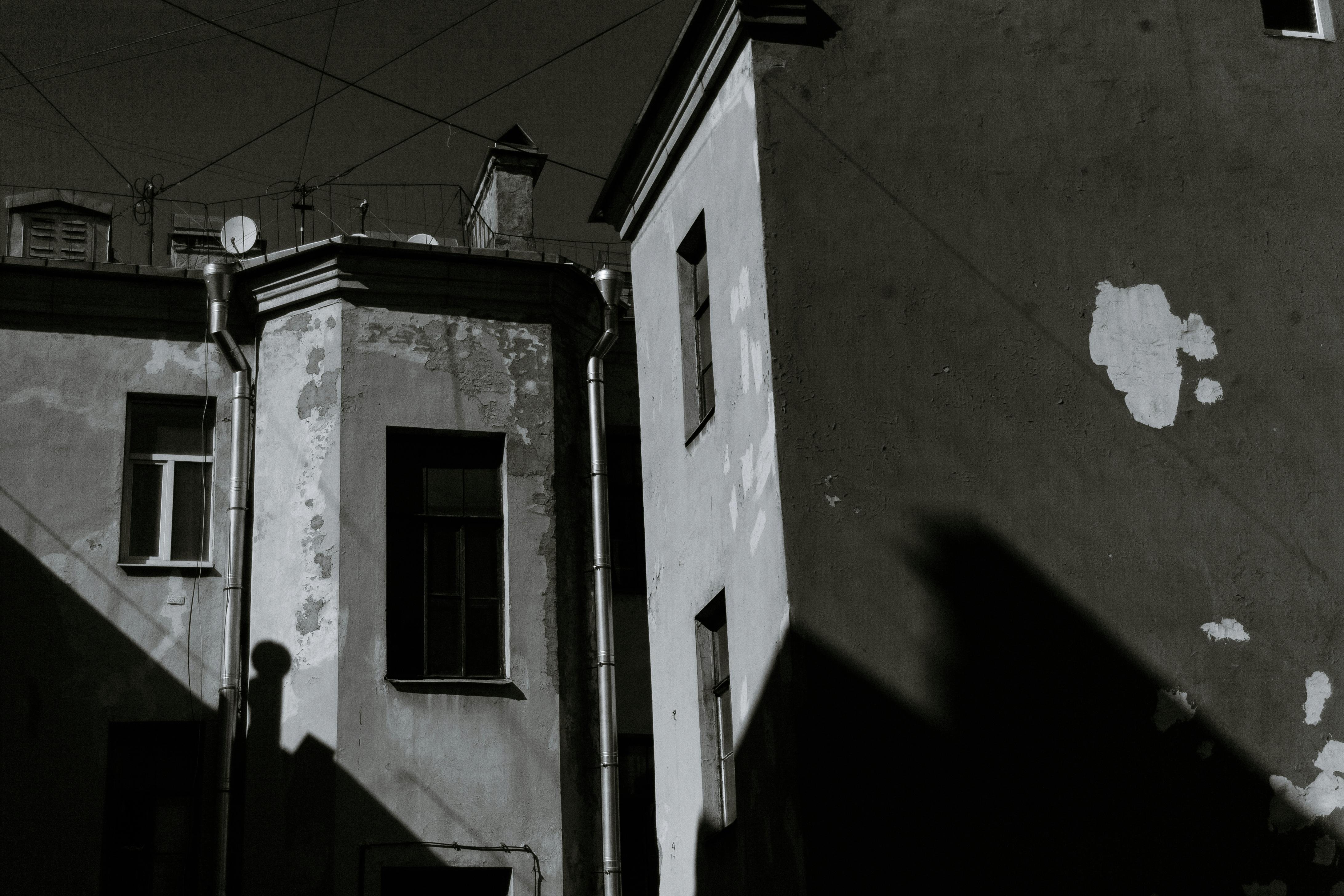 Free Black and white low angle facade of old building located on city street with windows and shadows on wall Stock Photo