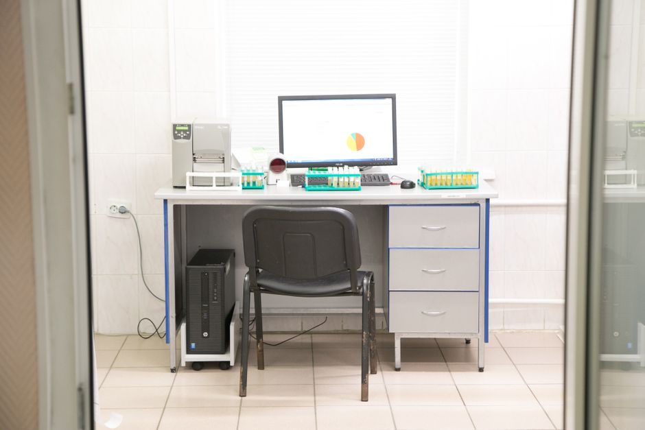 Contemporary workplace with various medical supplies and samples with computer placed on table in light room